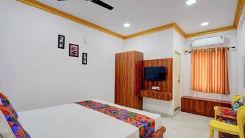Un dormitorio con dos camas, televisión, armario de madera y baño con cortina naranja.