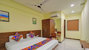 Ein Hotelzimmer mit Bett, Kleiderschrank, Schreibtisch und Deckenventilator.