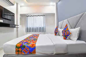 A modern hotel room with a bed, a TV, a window with curtains, and a wall-mounted air conditioner. - Fabhotel Div Palace (Indore)