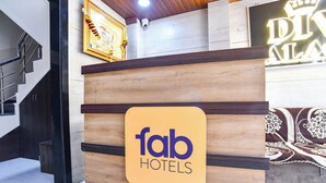 A reception desk with a sign for 'fab HOTELS' and a staircase to the left. - Fabhotel Div Palace (Indore)