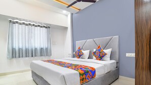 A modern bedroom with a grey bed, white bedding, and colorful geometric pillows. - Fabhotel Div Palace (Indore)