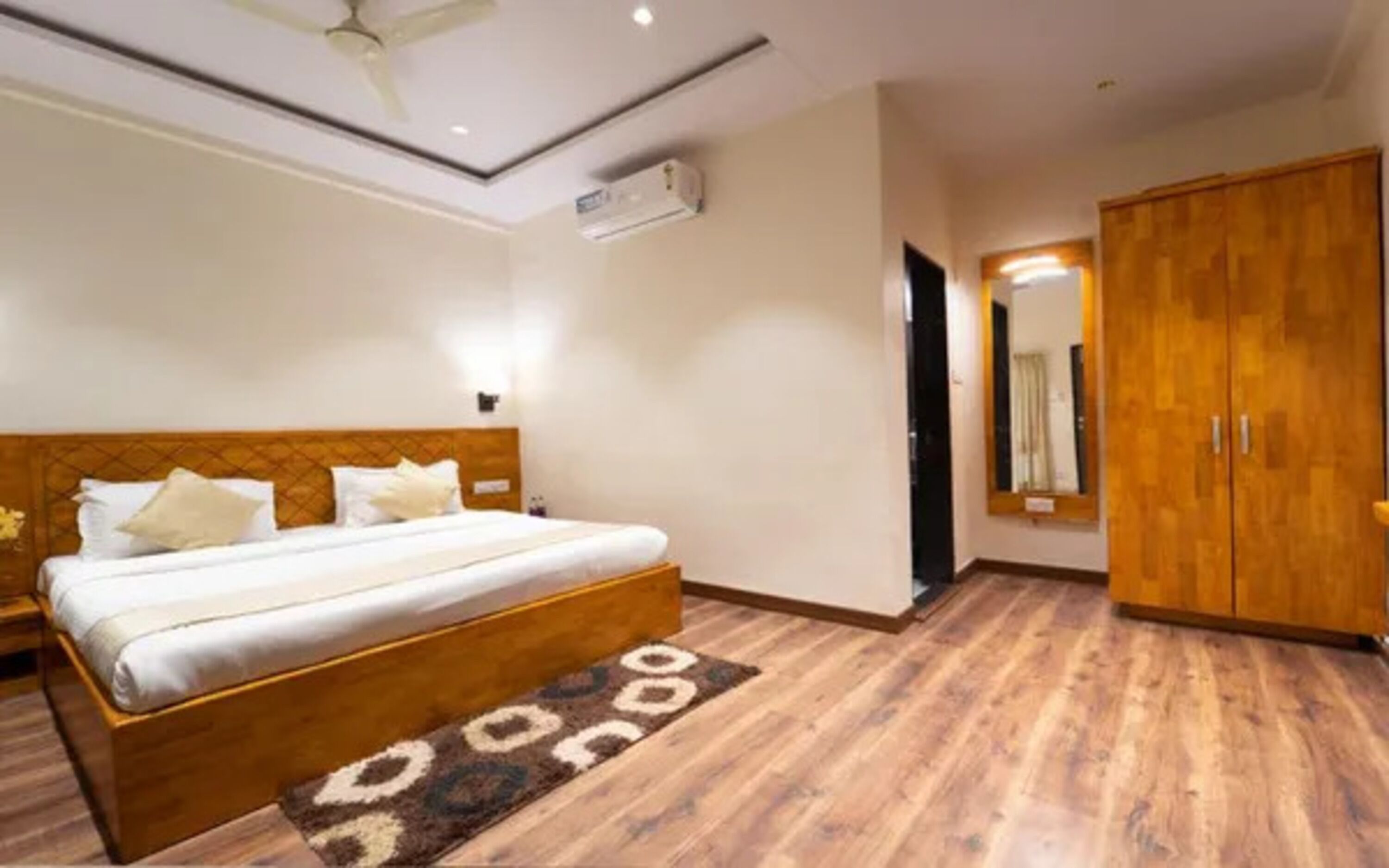 A hotel room with a wooden bed, a large wardrobe, and a ceiling fan.