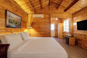 Une chambre dans une cabane en bois, avec un lit, un bureau et un tableau accroché au mur.