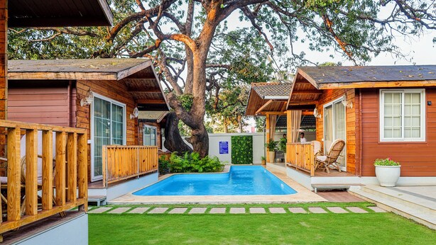 A wooden cabin with a swimming pool, surrounded by a well-maintained lawn and large trees. - FabHotel The Village Boutique Resort - Nr Chapora Fort, Vagator (Vagator)