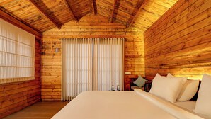 A wooden cabin room with a bed, a window with curtains, and a radiator. - FabHotel The Village Boutique Resort - Nr Chapora Fort, Vagator (Vagator)