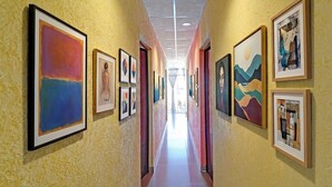 Un passadís amb obres d'art emmarcades a les parets, un paviment de rajoles i un sostre amb il·luminació empotrada.