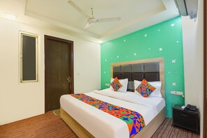 A hotel room with a bed, a ceiling fan, a wooden door, and a green wall with white stars. - Fabhotel Pp Residency By Yellow Saffron (New Delhi)
