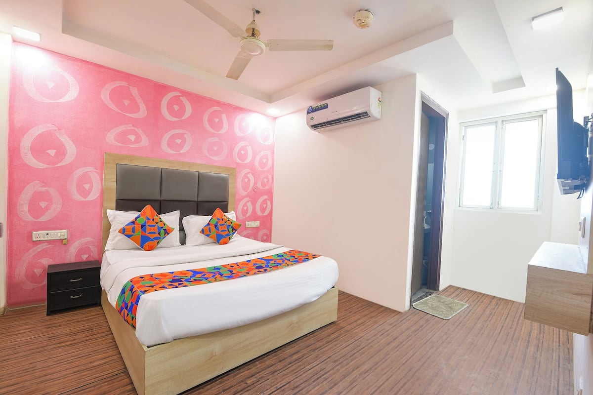 Een slaapkamer met een bed, nachtkastje, plafondventilator, airconditioning en een raam.