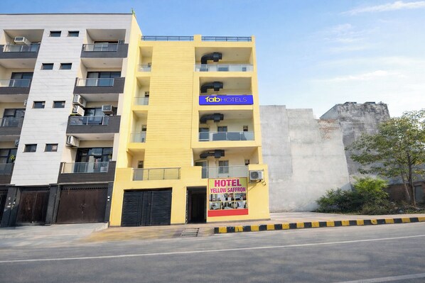 A yellow multi-story building with balconies, a sign for 'Tab Hotels,' and a 'Hotel Yellow Saffron' sign. - Fabhotel Pp Residency By Yellow Saffron (New Delhi)