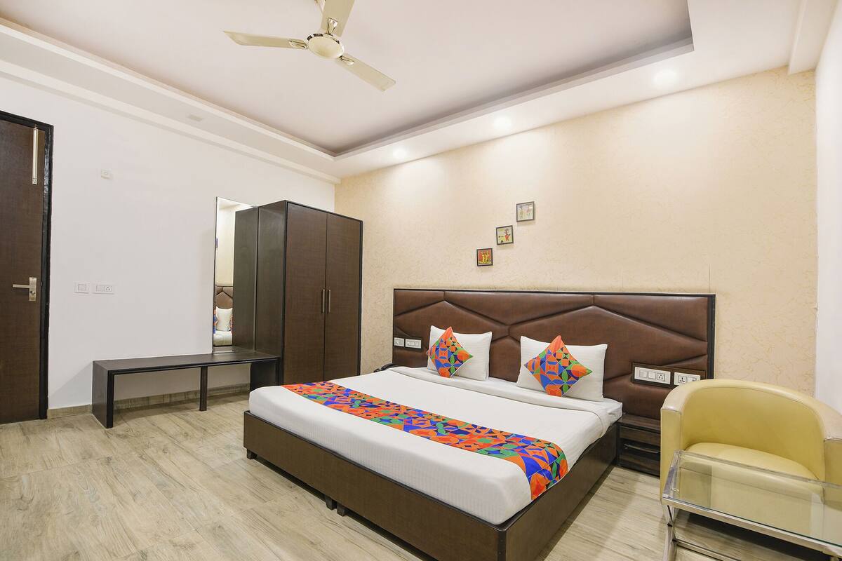 Une chambre à coucher comprenant un lit, une armoire, un bureau, une chaise et un ventilateur de plafond.
