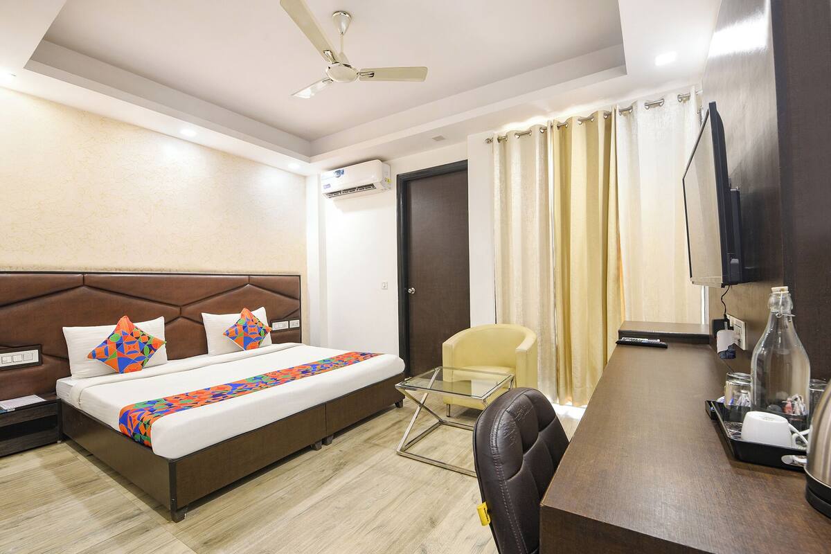 Une chambre d’hôtel équipée d’un lit, d’un bureau, d’une chaise, d’une télévision et d’un ventilateur de plafond.
