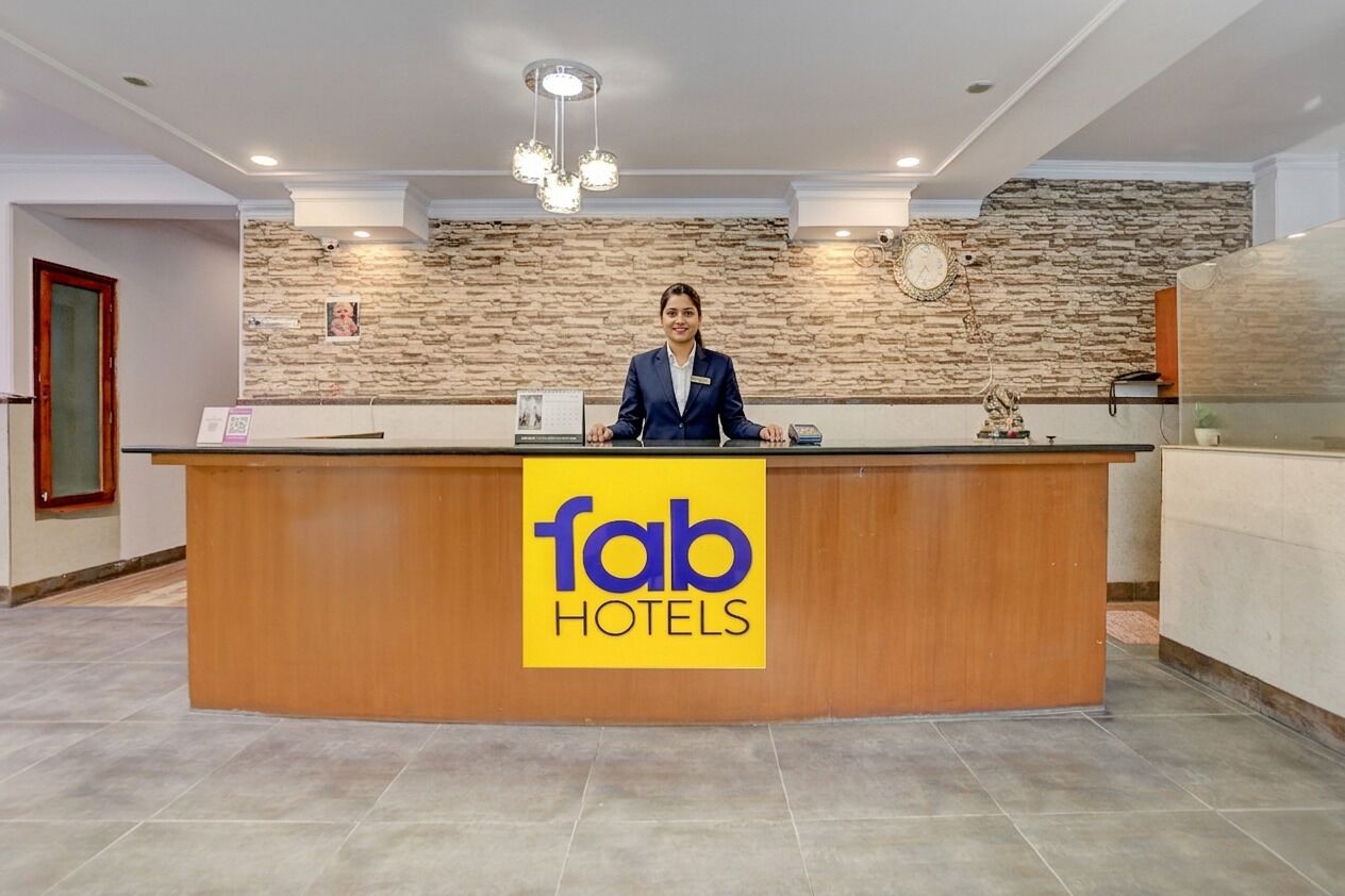 A reception desk with a 'fab hotels' sign, a receptionist, a stone wall, and a clock.