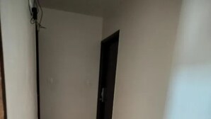 Passadís estret amb sòl de rajoles i parets sense decoració.