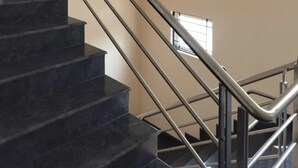 Una escala amb graons de marbre negre i baranes d'acer inoxidable, que condueix a un pis superior.