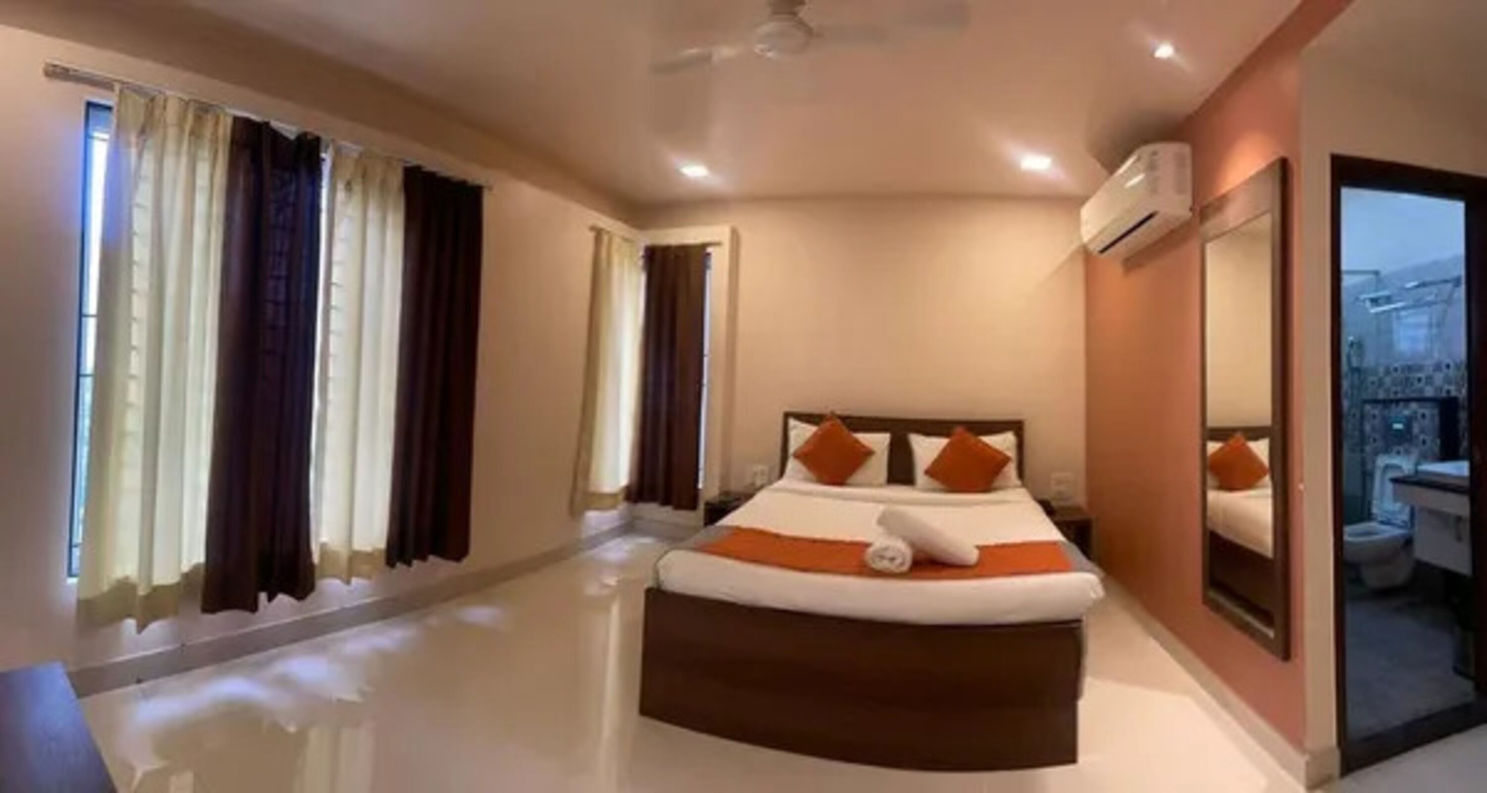 A hotel room with a large bed, a ceiling fan, and a view of the outside through the window.