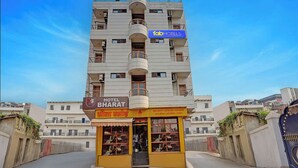 Un hotel a più piani con balconi, un cartello con la scritta 'Hotel Bharat' e un'insegna con la scritta 'fabHOTELS' sopra.