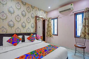 A bedroom with a bed, a chair, a window, and an air conditioner. - Fabhotel Bharat (Varanasi)