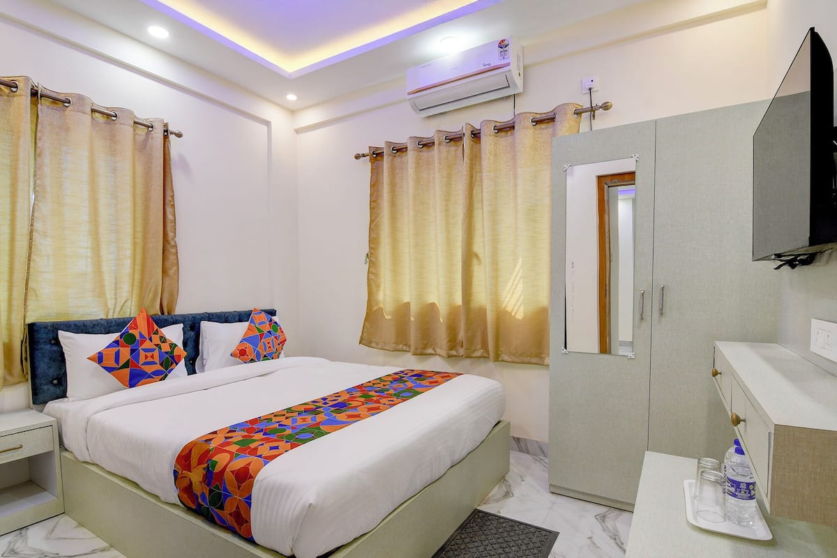 Een hotelkamer met een bed, een kledingkast, een kaptafel met spiegel en een airconditioning.