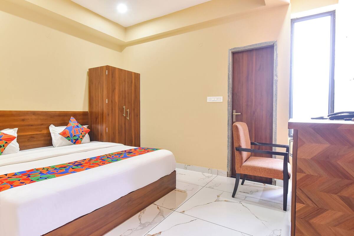 Una habitación de hotel con cama, armario, silla y escritorio.