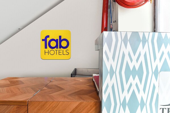 A hotel room with a wooden table, a patterned wall, and a 'fab hotels' sign. - Fabhotel The Castle (Jaipur)