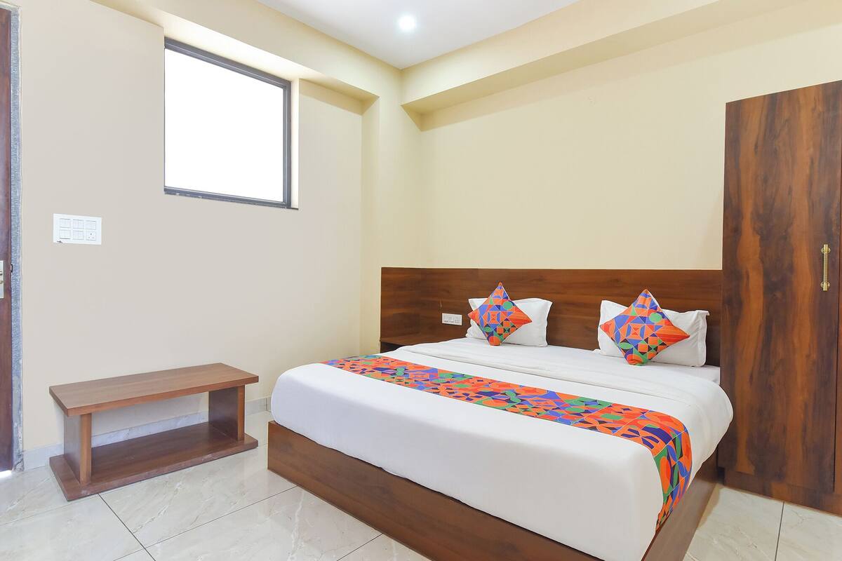Un dormitorio con cama, cabecera de madera, un banco y un armario.