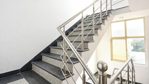 Eine Treppe mit Metallgeländern und Granitstufen, die zu einem Raum mit einem großen Fenster führt.