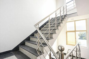 A staircase with metal railings and granite steps, leading to a room with a large window. - Via Nishka Residency (New Delhi)