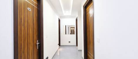 A hallway with wooden doors, a tiled floor, and a ceiling with recessed lighting.