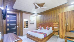 Ein Schlafzimmer mit einem Holzbett, einem Deckenventilator, einem Schrank aus Holz und einem kleinen Schreibtisch mit Fernbedienung.