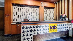 A hotel reception desk with a wooden finish, a clock, and a 'fab hotels' sign. - Fabhotel Olive Grand (Chennai)