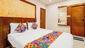 A hotel room with a bed, a wooden headboard, a large abstract painting, a mirror, and a wooden wardrobe. - Fabhotel Olive Grand (Chennai)