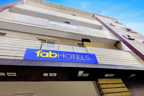 A hotel sign with the name 'fab hotels' and a multi-story building with balconies and windows.