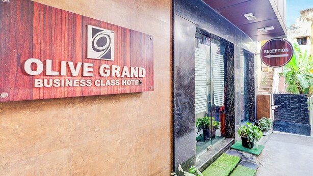 The exterior of Olive Grand Business Class Hotel with a reception sign, a wooden facade, and a glass entrance. - Fabhotel Olive Grand (Chennai)