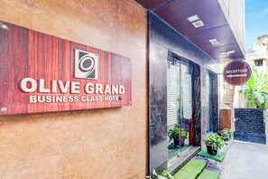The exterior of Olive Grand Business Class Hotel with a reception sign, a wooden facade, and a glass entrance. - Fabhotel Olive Grand (Chennai)