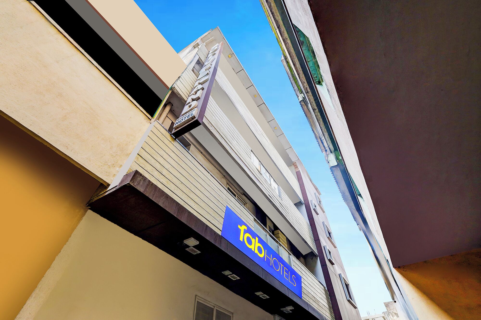 Un hôtel avec une enseigne bleue, un balcon et un ciel dégagé.