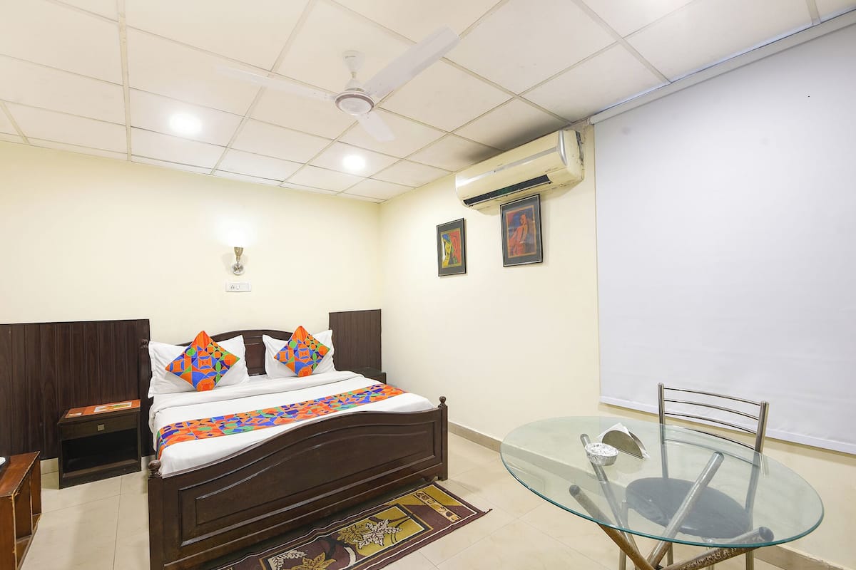 A bedroom with a bed, bedside tables, a glass table, and a ceiling fan.