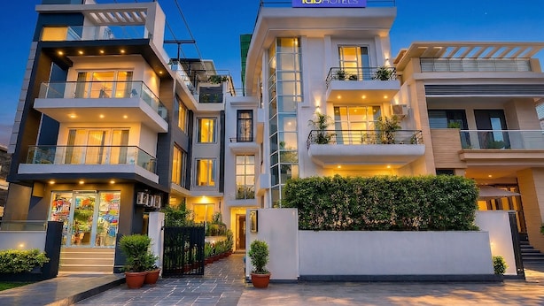 A multi-story hotel with balconies, a storefront, and a well-lit entrance. - Fabhotel Guru Kripa Residency (Gurugram)