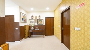 A hotel lobby with wooden doors, a reception desk, framed artwork, and a no-smoking sign. - Fabhotel Guru Kripa Residency (Gurugram)
