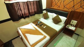 A hotel room with a bed, pillows, a bedside table, and a small cabinet. - Fabhotel Star Hill (Mumbai)