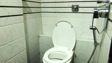 Un baño pequeño y moderno con inodoro, bidé y un cubo negro etiquetado 'JOYYO'.