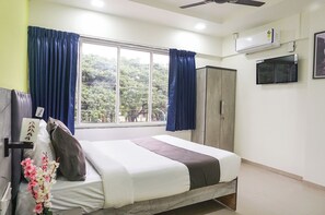 A bedroom with a bed, curtains, a wardrobe, a ceiling fan, an air conditioner, and a TV. - Fabhotel Vardhan Plaza (Pune)