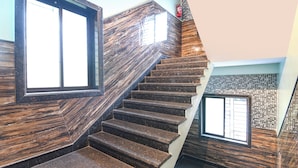 Eine Treppe mit Holzboden und Wänden, die zu einer Zwischenebene mit einem Fenster führt.