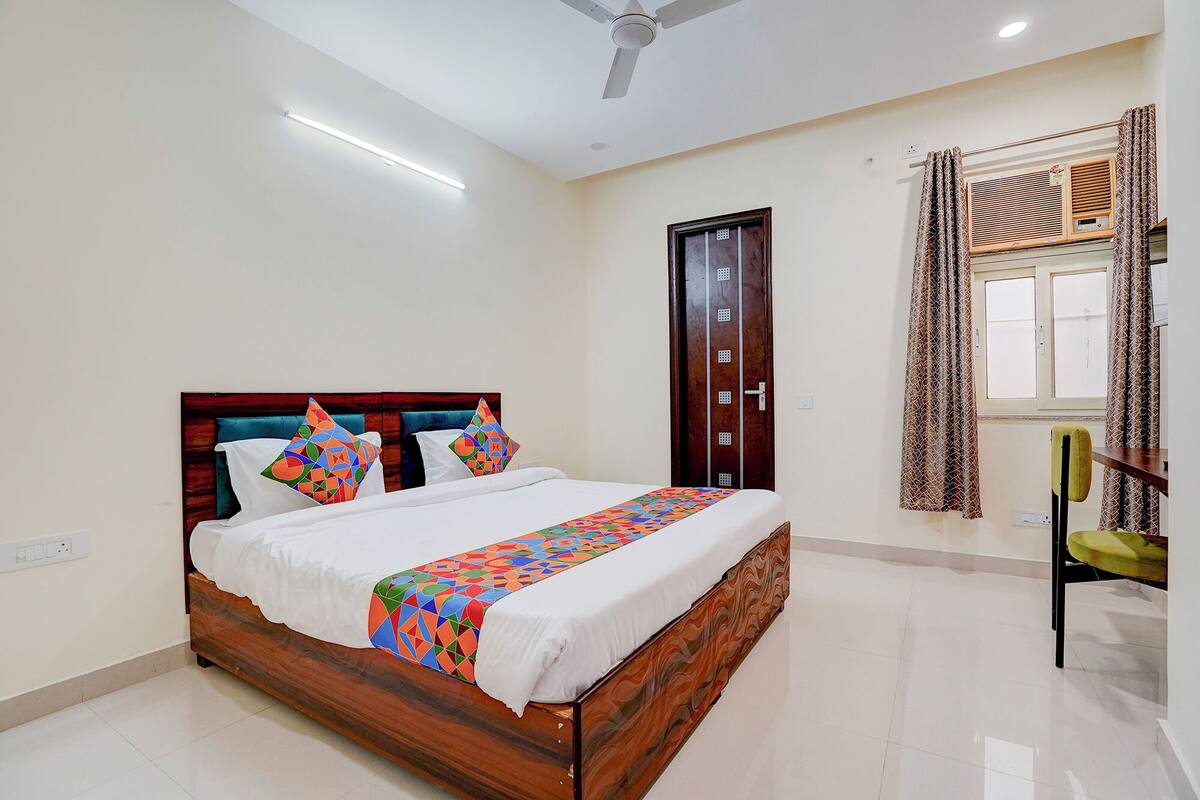 A neatly arranged bedroom with a wooden bed, a ceiling fan, a window with curtains, and a radiator.