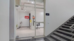 A hotel entrance with a glass door, a sign indicating the 3rd floor, and a chair near the door. - Fabhotel Cozy Stay (Noida)