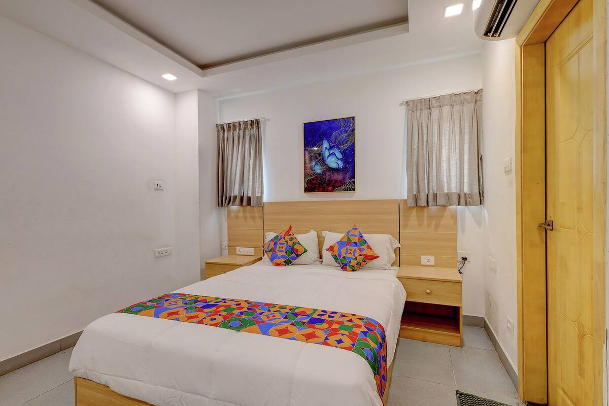 A bedroom with a bed, two nightstands, a wooden headboard, a painting, and a door.