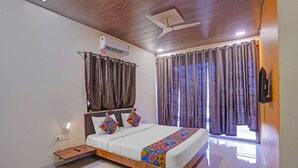Une chambre à coucher avec un lit, des rideaux, un ventilateur de plafond et un appareil de climatisation.