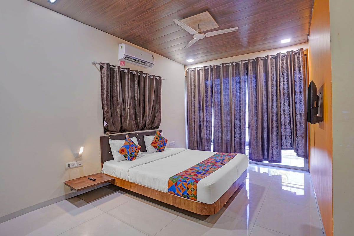 A bedroom with a bed, curtains, a ceiling fan, and an air conditioning unit.