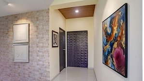 Un couloir avec un mur en briques, des œuvres d’art encadrées, une porte et une peinture abstraite aux couleurs vives.