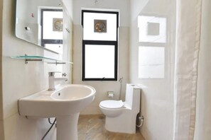 Un baño con lavamanos blanco, inodoro y espejo sobre el lavamanos.
