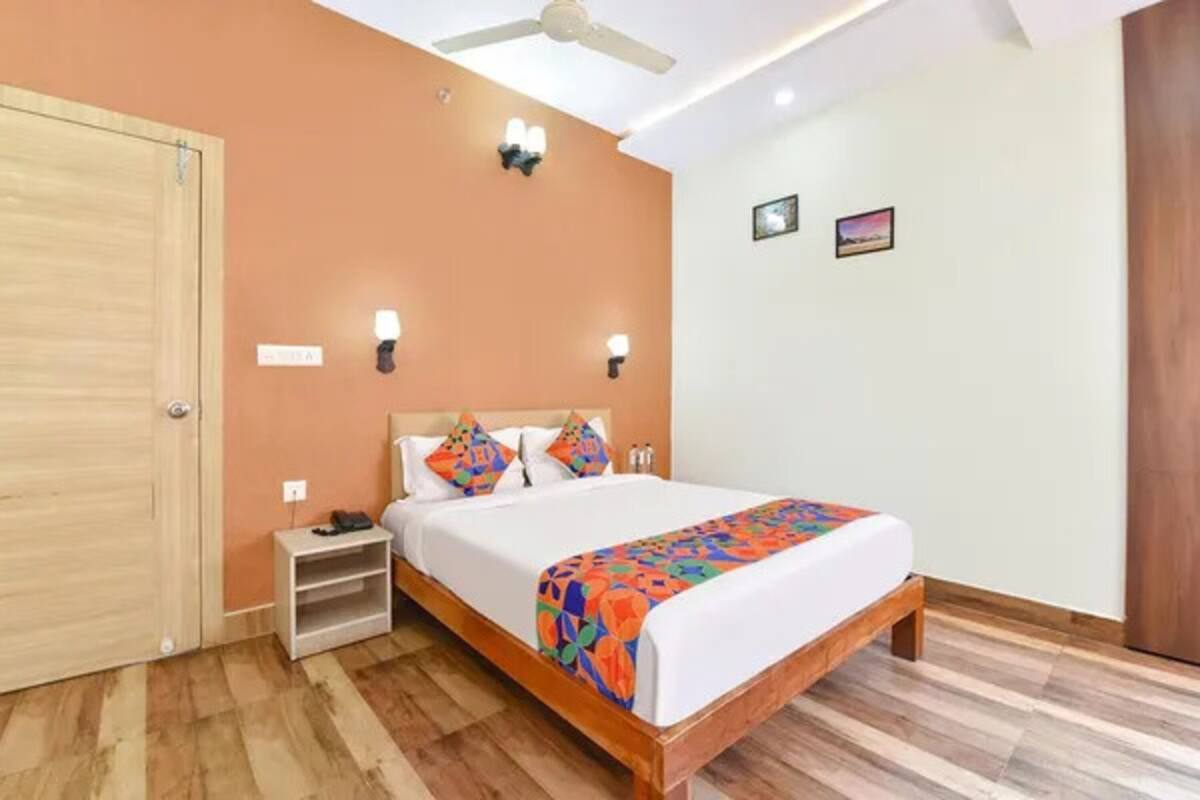 Une chambre avec un lit en bois, une table de chevet, un ventilateur de plafond et une porte.
